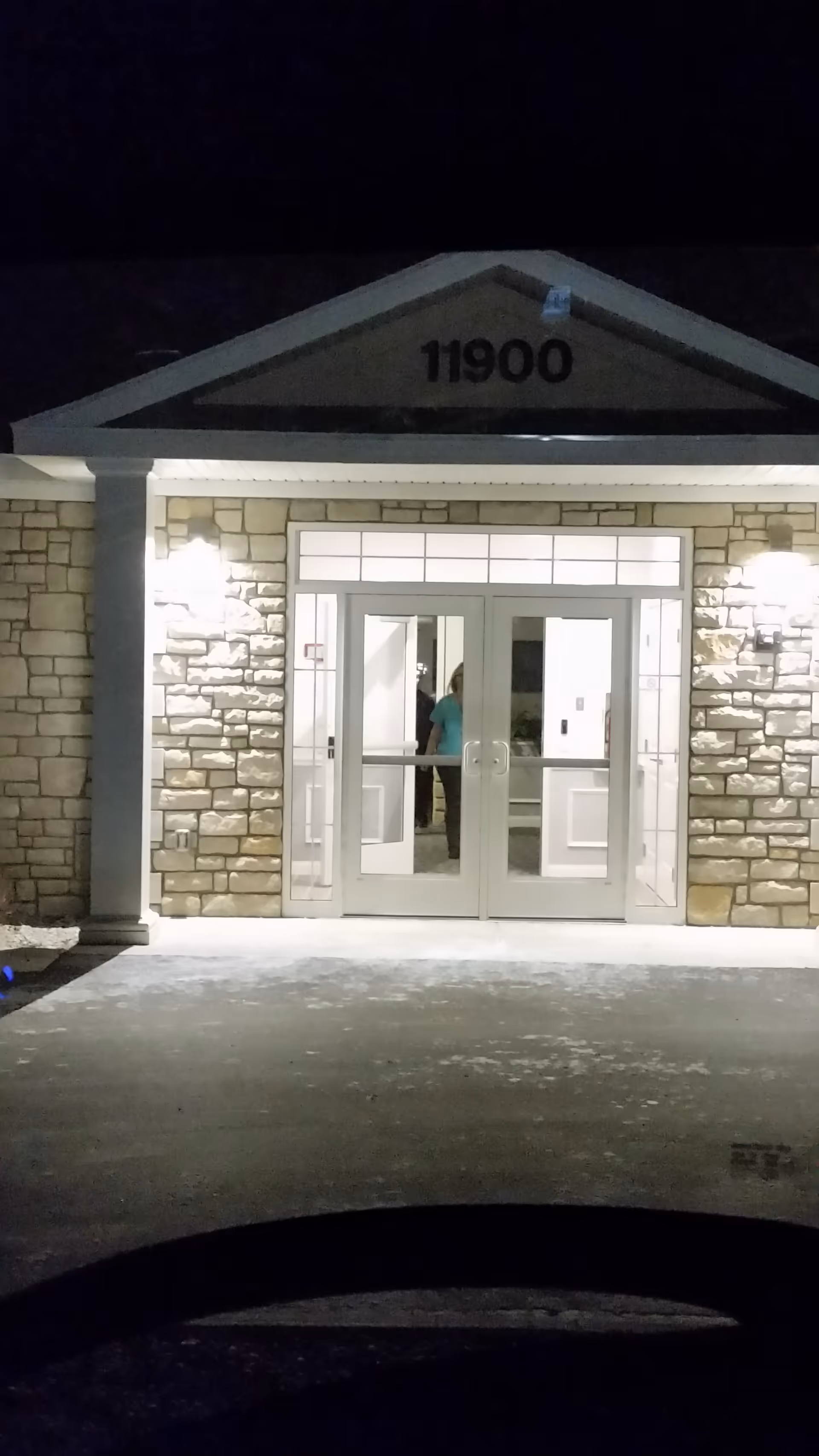 Nighttime exterior of a stone Vista Springs entrance with glass doors and 11900.