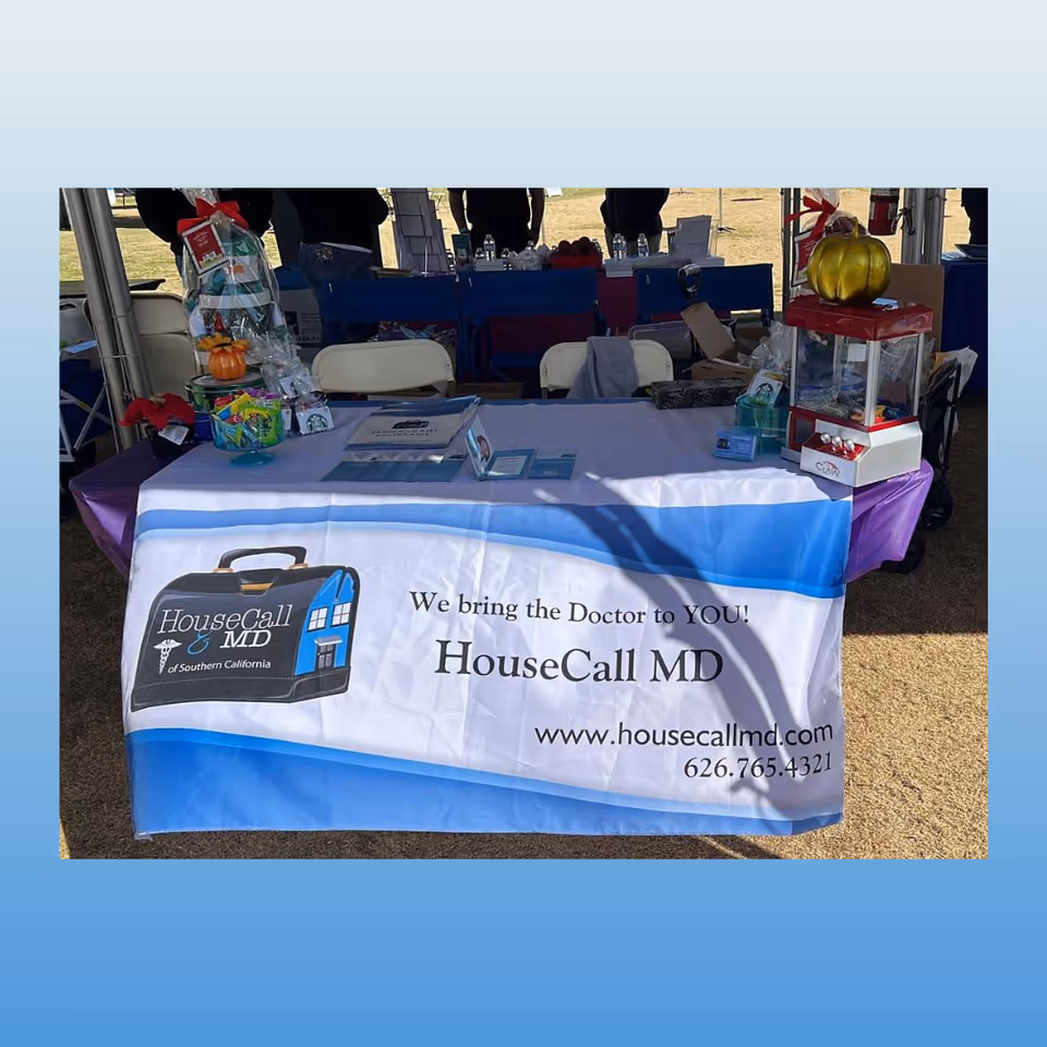 Outdoor event booth for HouseCall MD with banner and promotional materials on a table