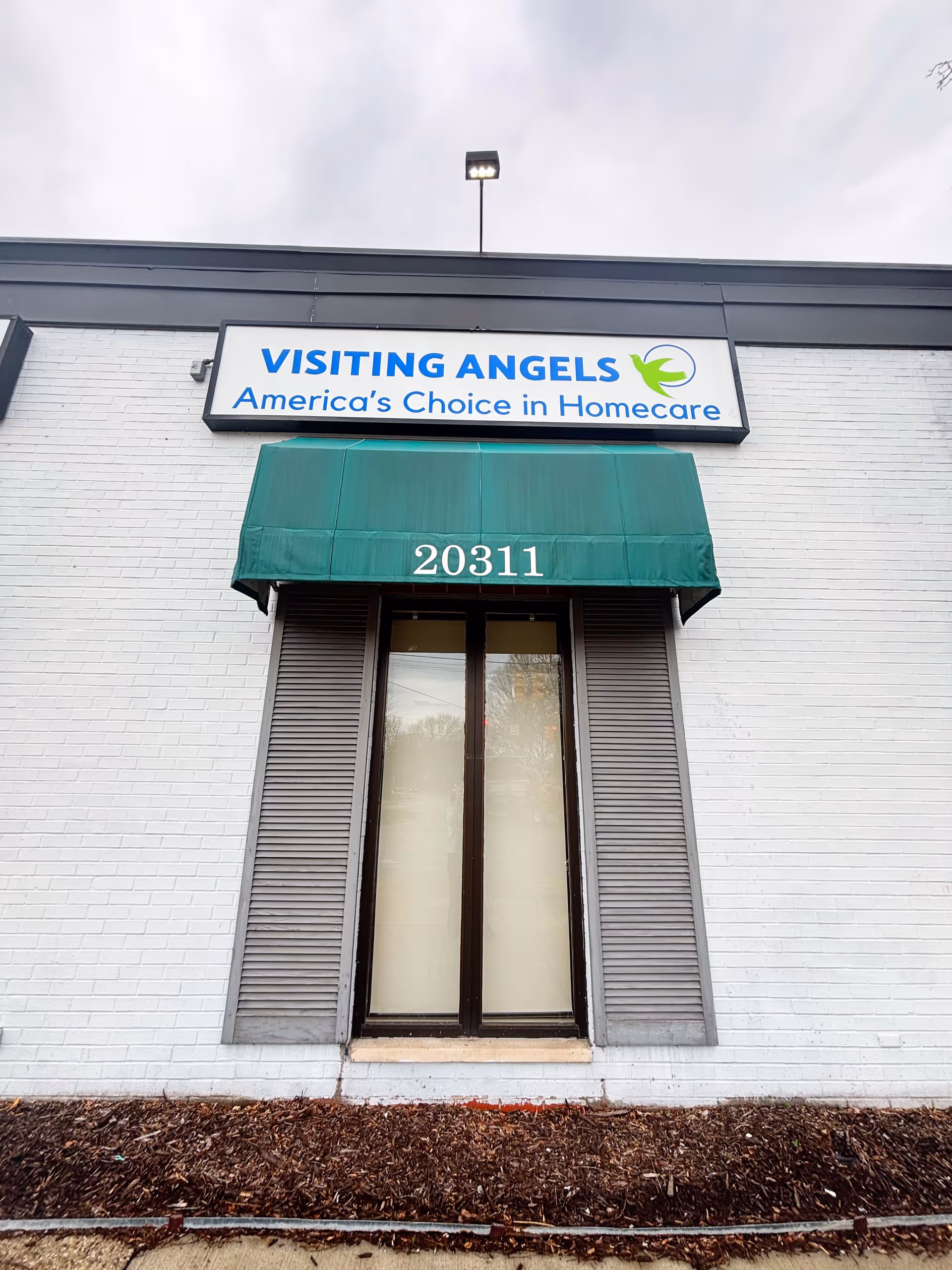 Exterior of Visiting Angels office building with green awning and address 20311.
