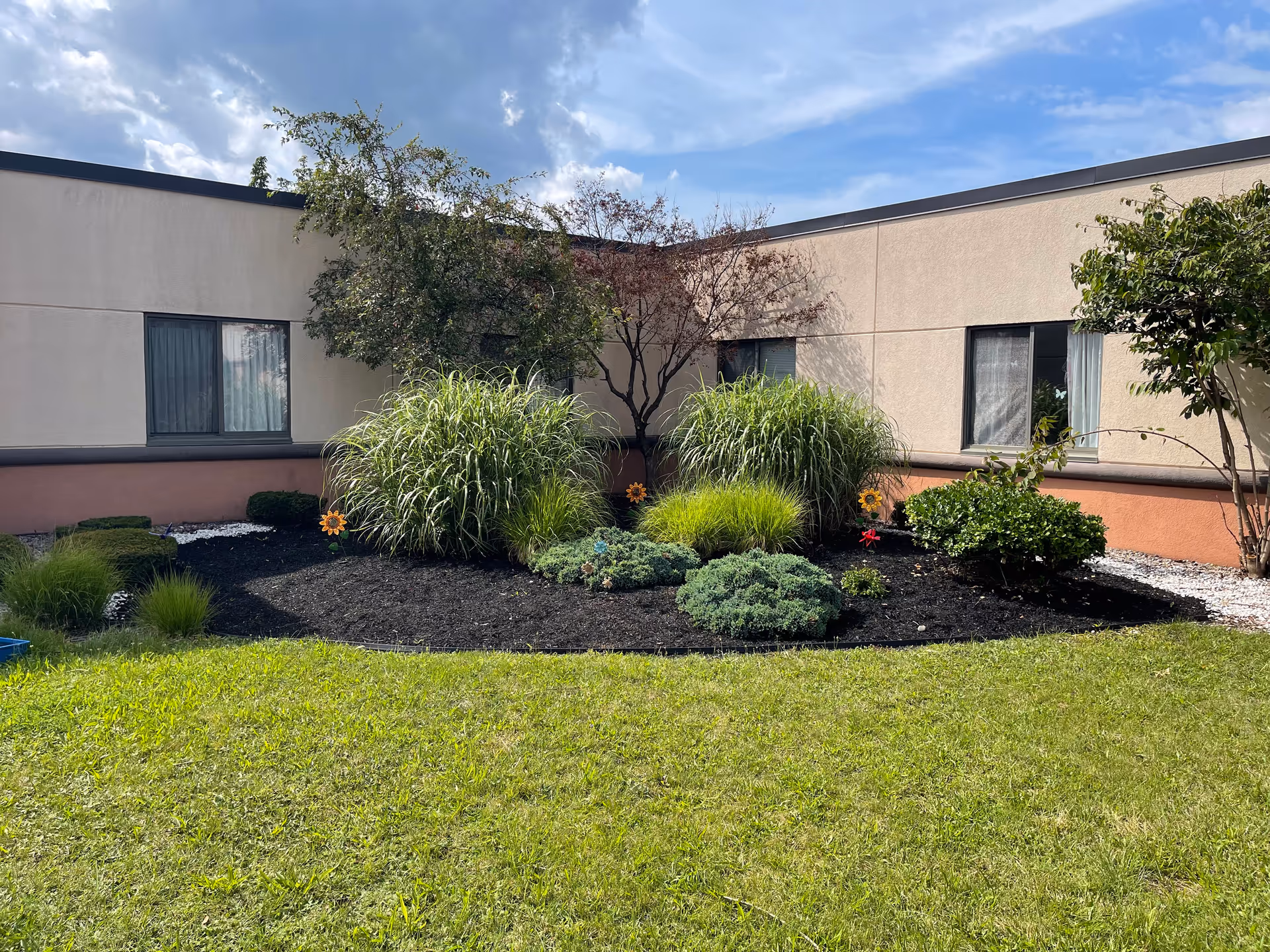 Exterior view of Harris Hill Nursing Facility with landscaped front garden and windows.