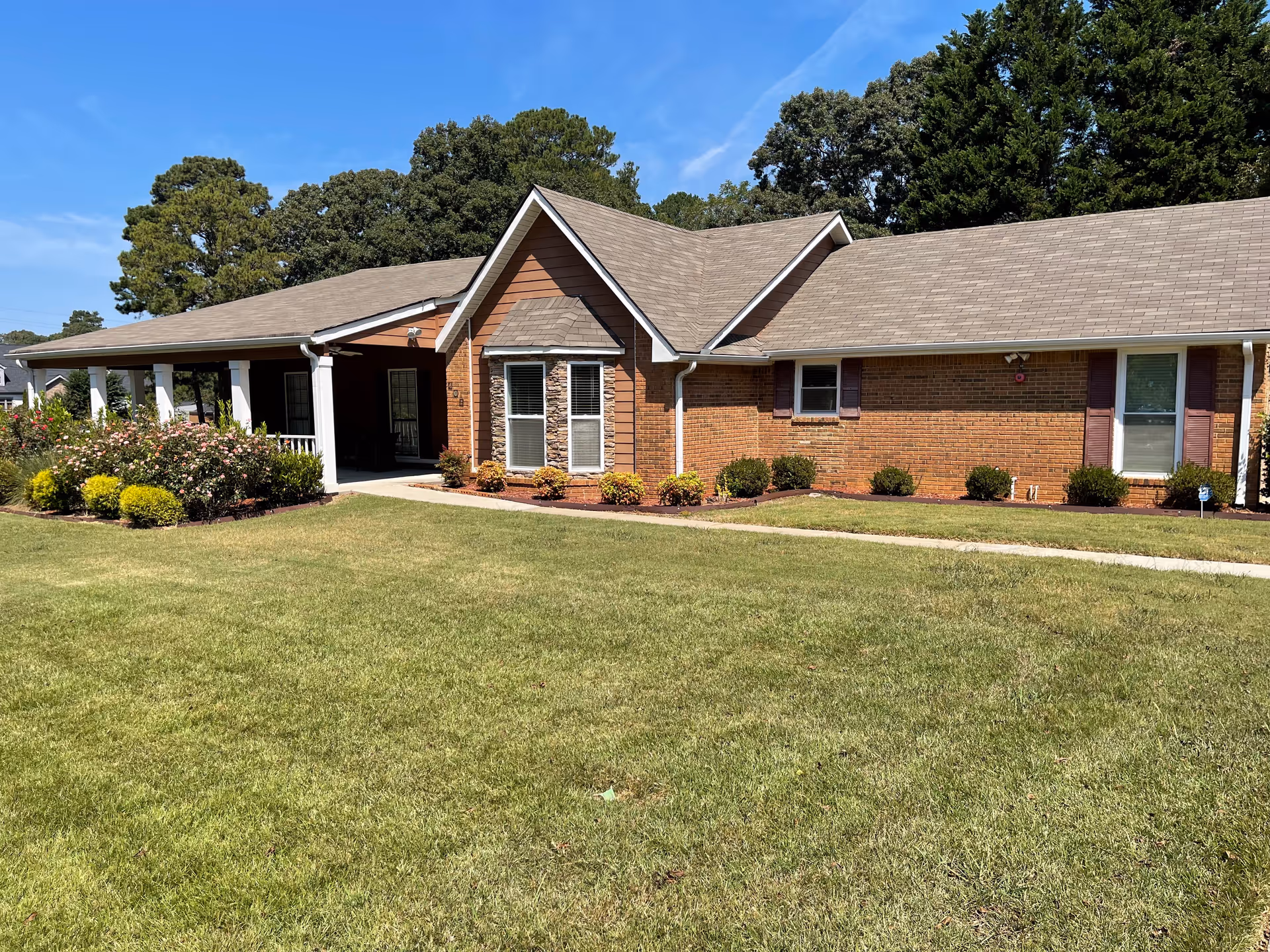 Single-story brick senior living facility with manicured lawn and a covered entrance.
