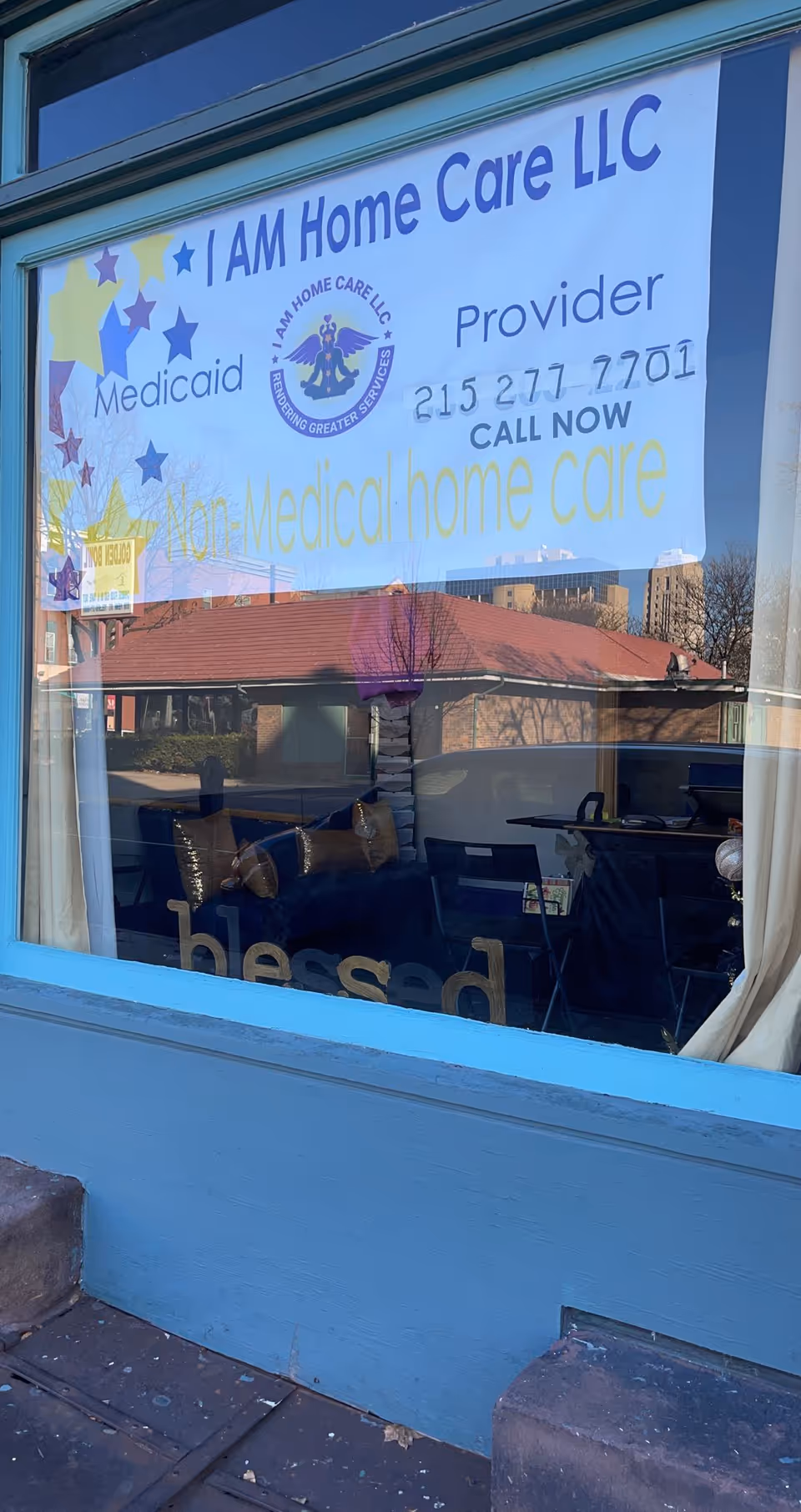 Window sign advertising I AM Home Care LLC on a blue building exterior.