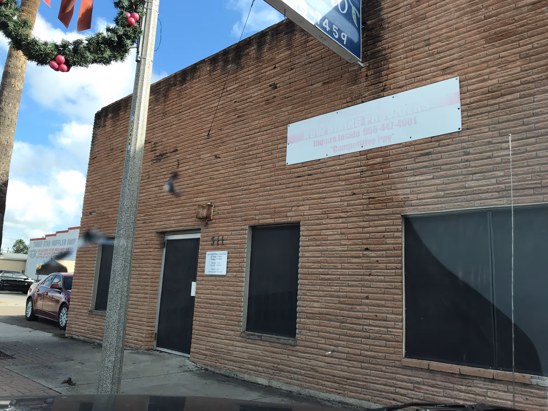 Brick building exterior with a large blank sign and a parked car nearby.