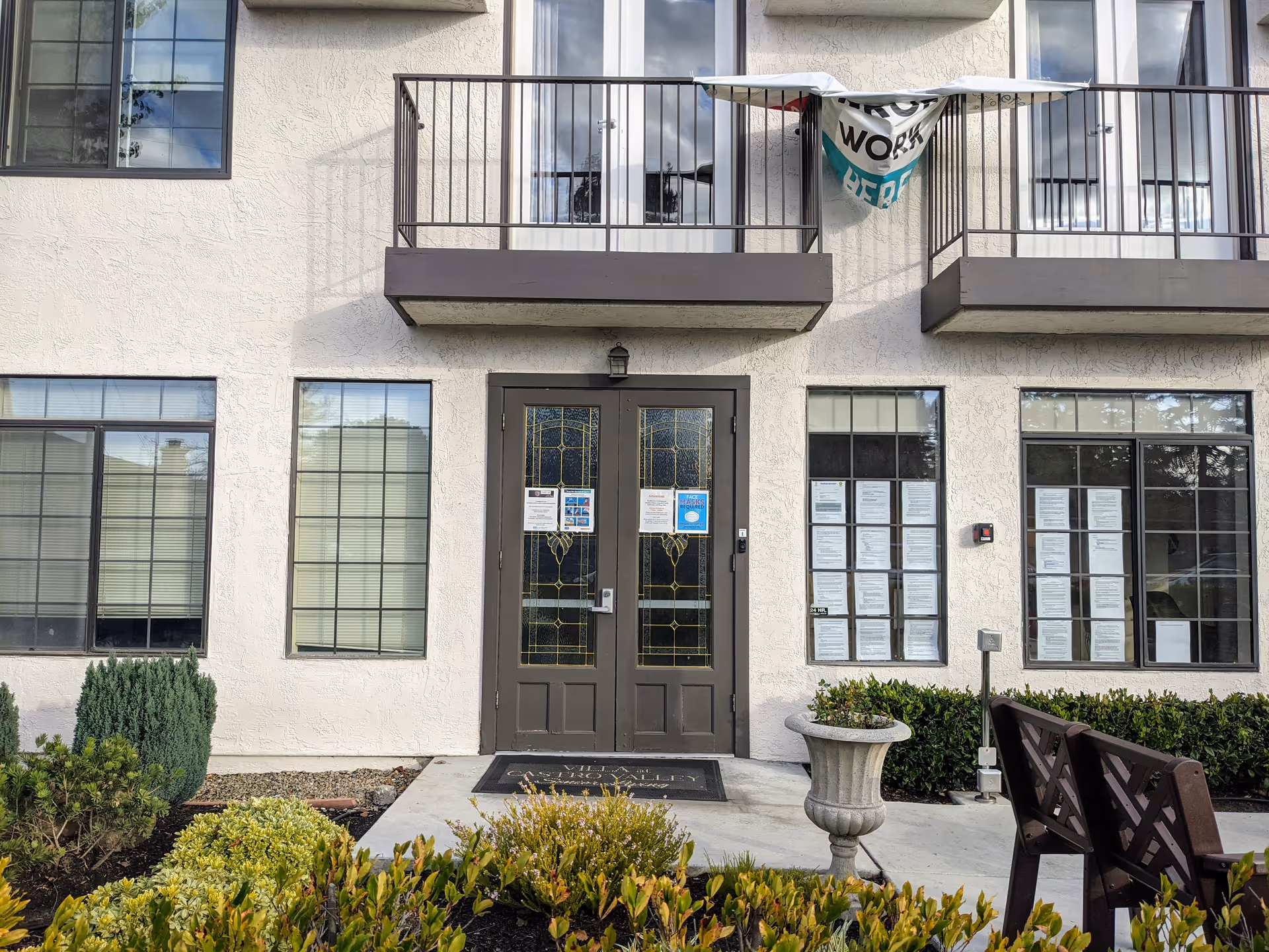 Front exterior of Carefield Castro Valley featuring double doors, windows, and balconies.