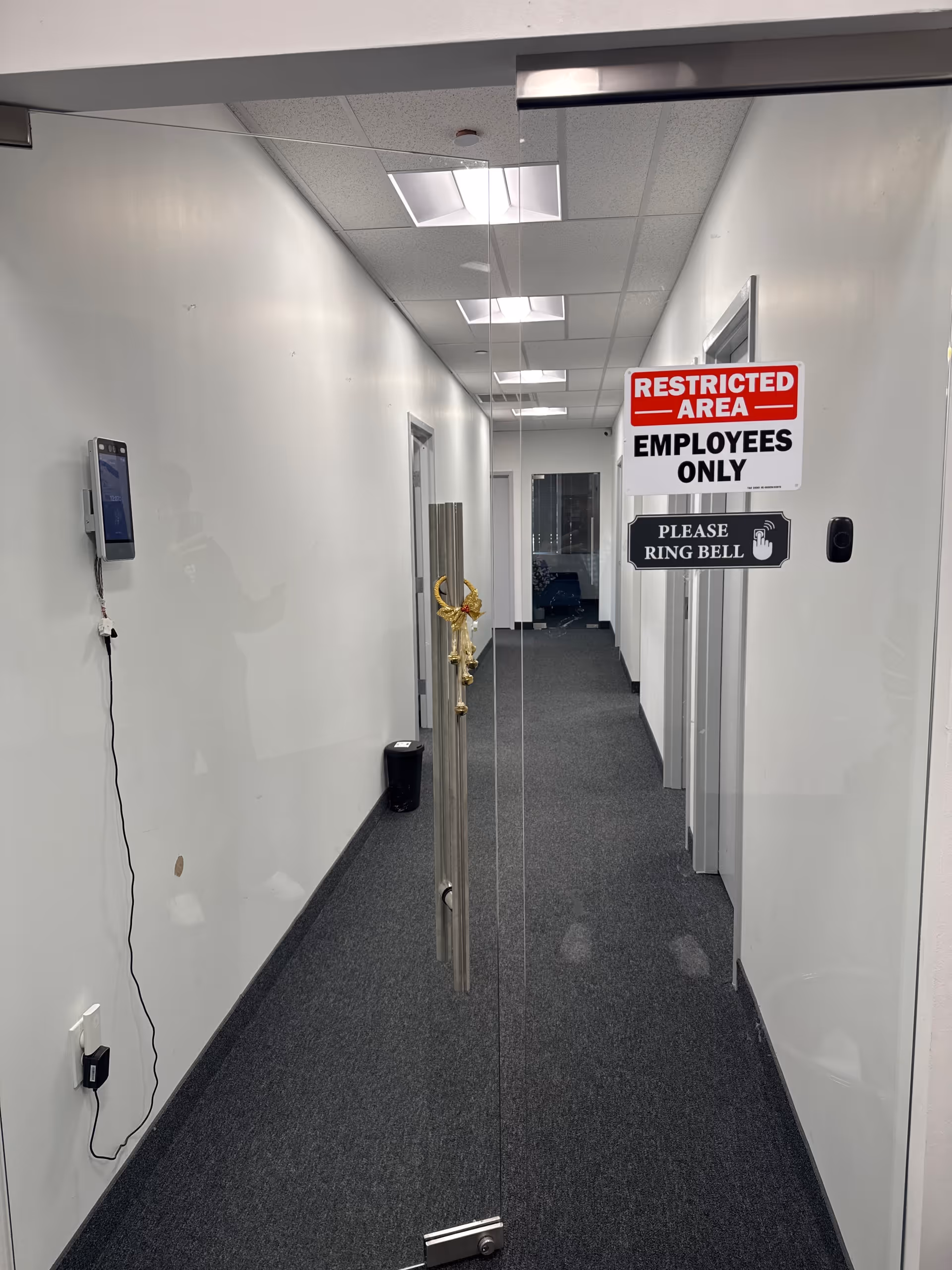 Long interior corridor with glass doors and 'Restricted Area - Employees Only' sign.