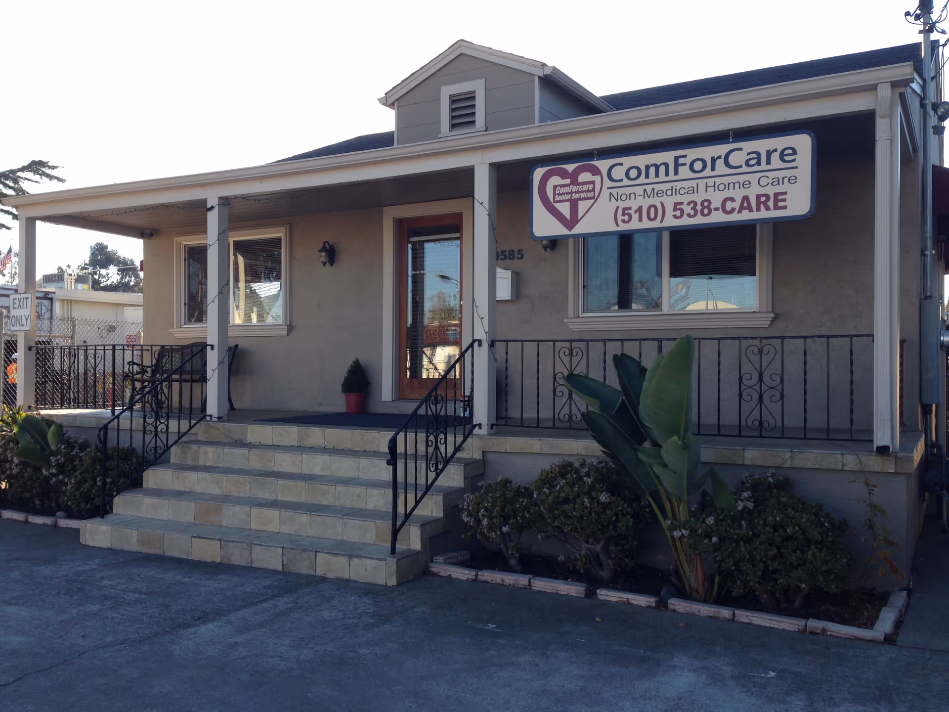 Single-story beige building with a ComForCare sign and front steps leading to a glass door