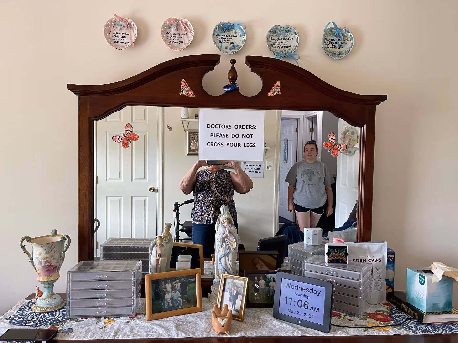 Wooden dresser with mirror, keepsakes, photos, and a digital clock on the table.