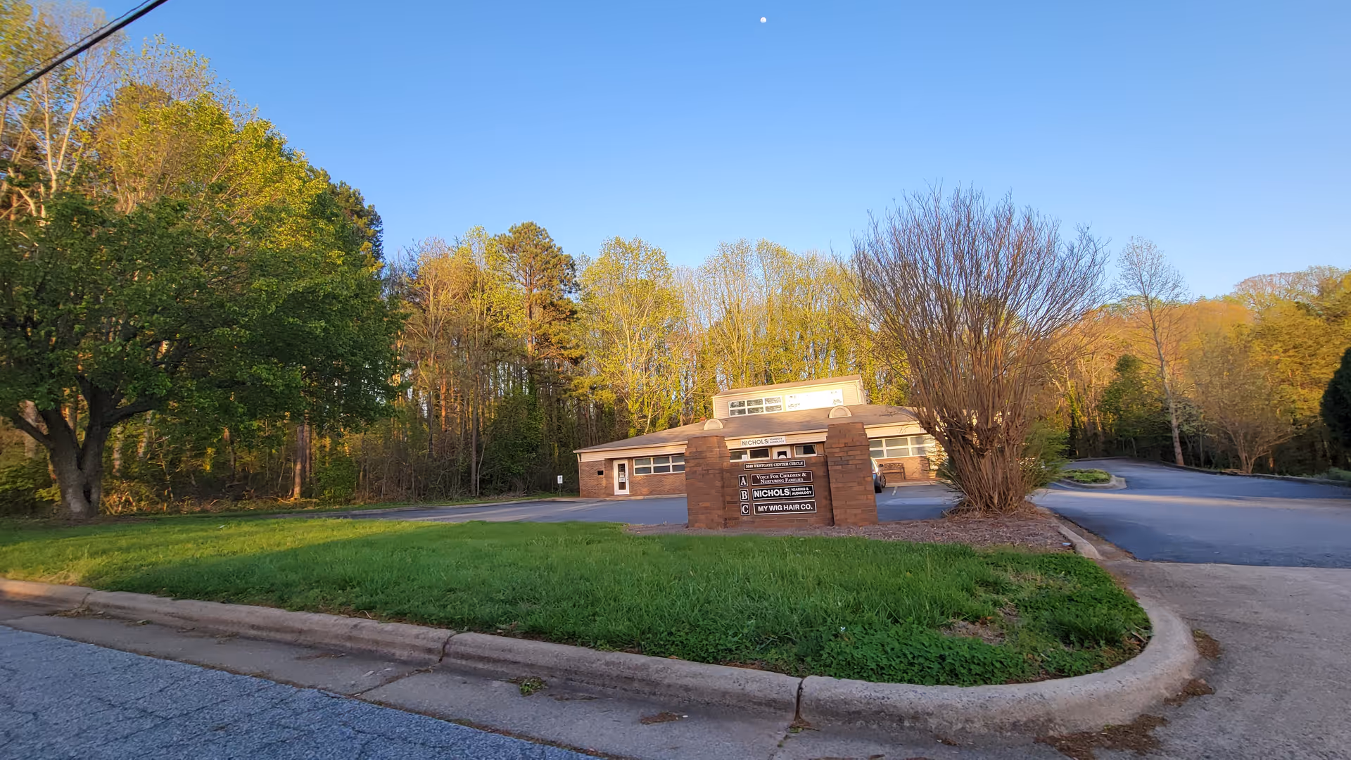 Infinity Care Services building entrance with a sign, trees, and a curved driveway.
