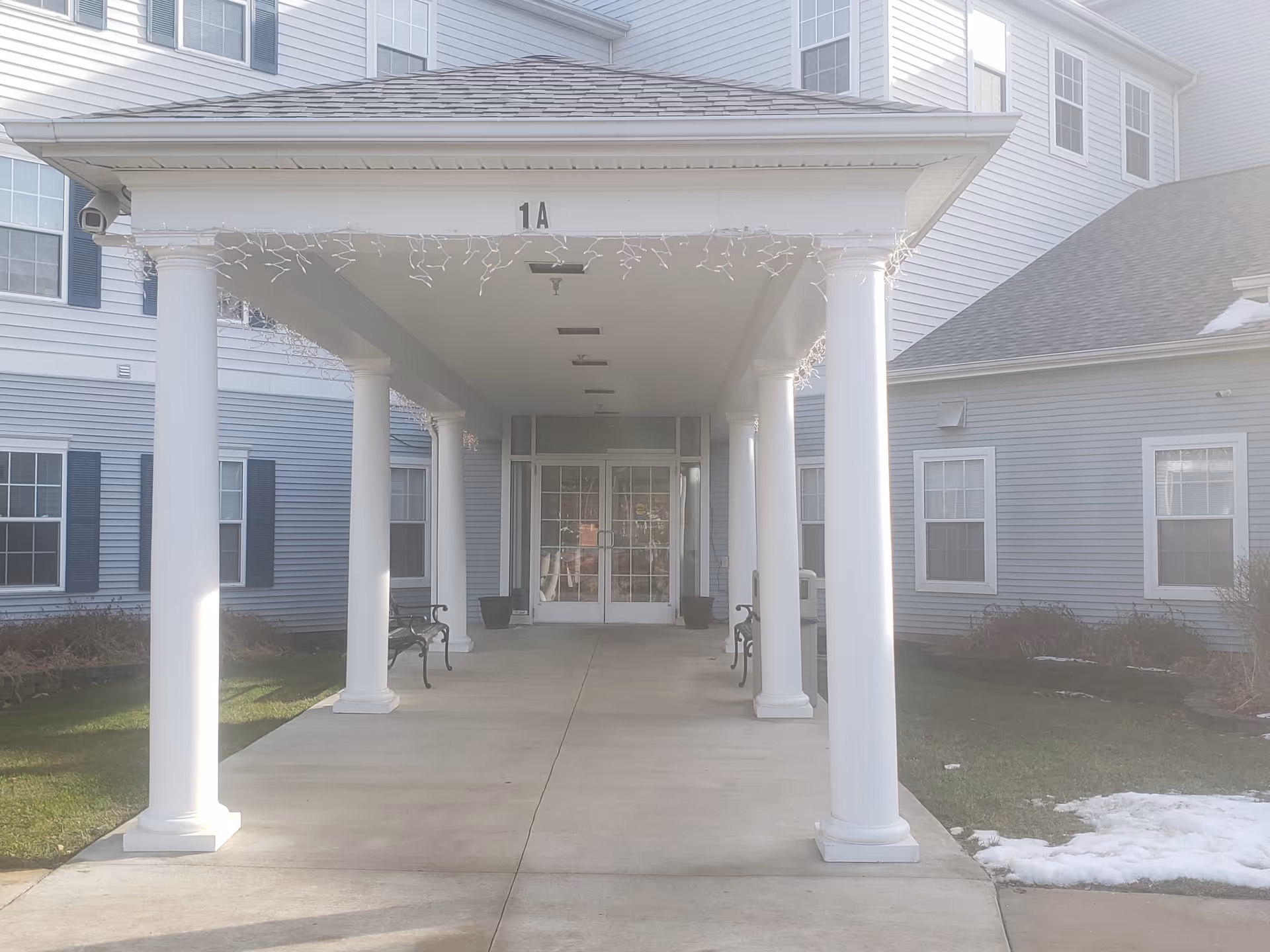 Front entrance of a senior living facility with white columns and a covered walkway.