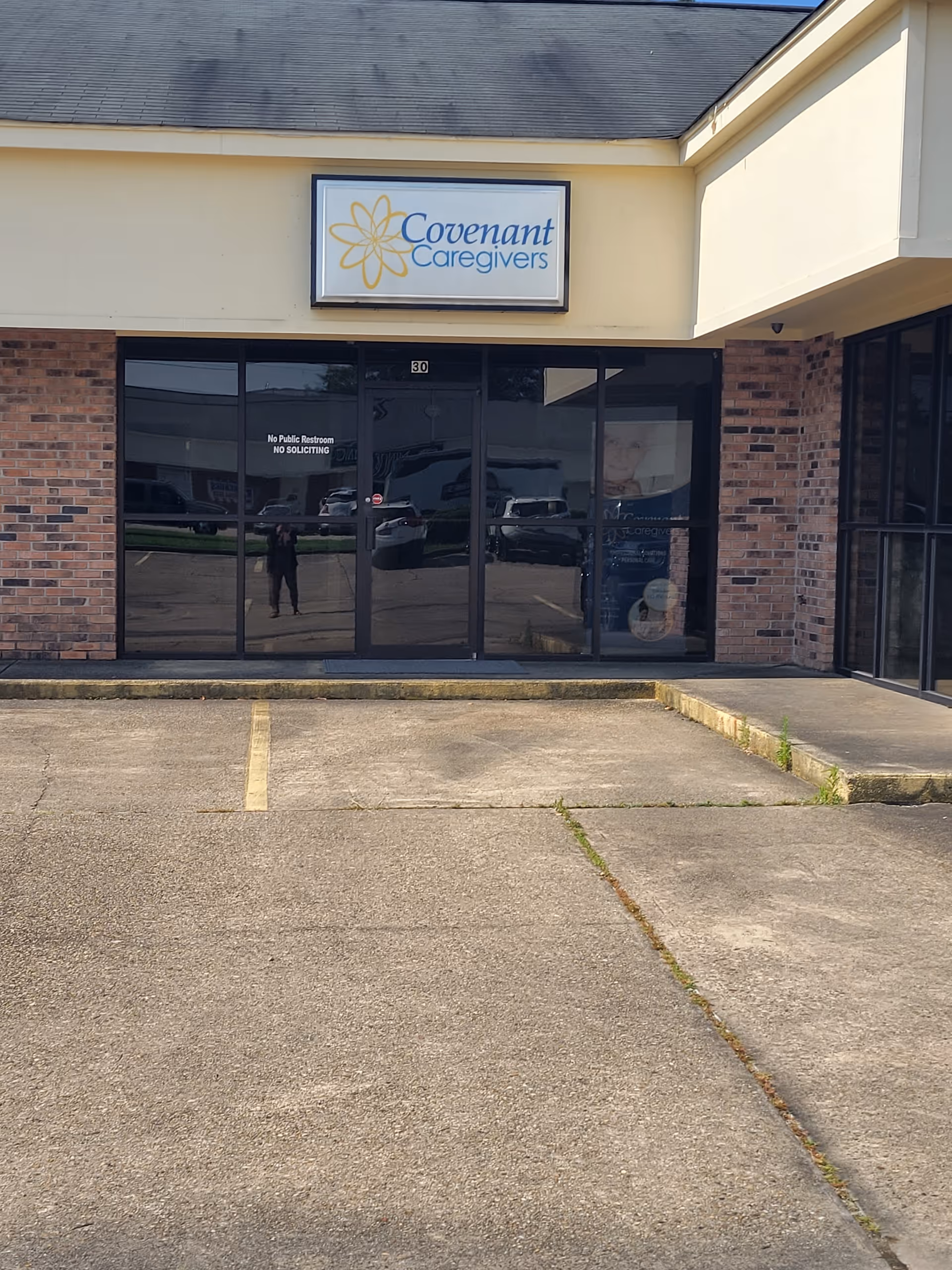Exterior view of Covenant Caregivers - Home Care storefront with glass doors and parking lot.