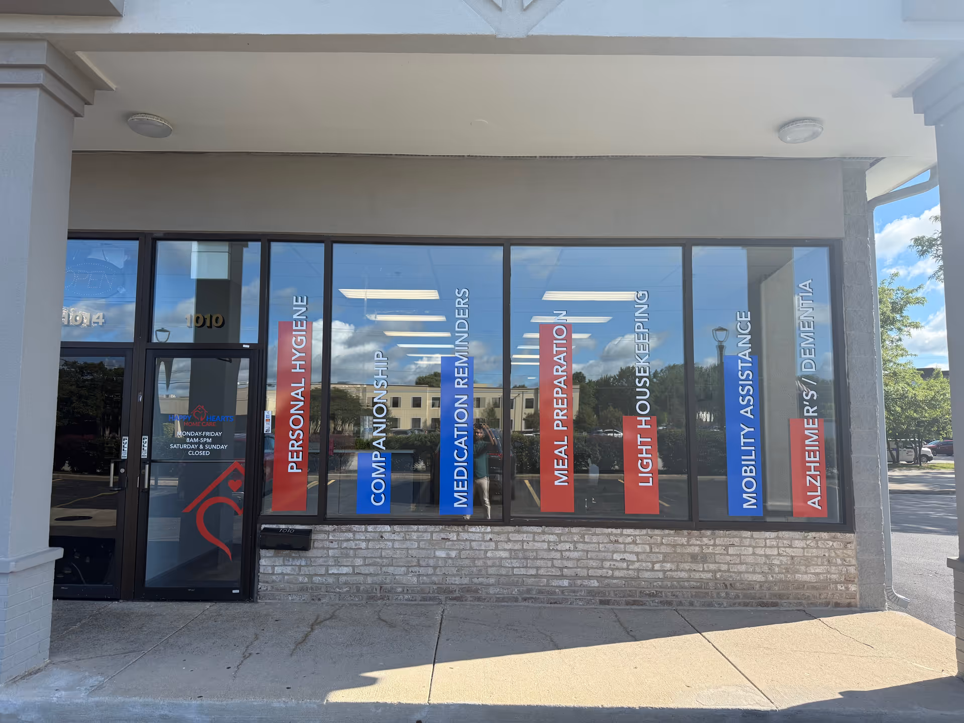 Storefront with large glass windows and vertical banners listing caregiving services.