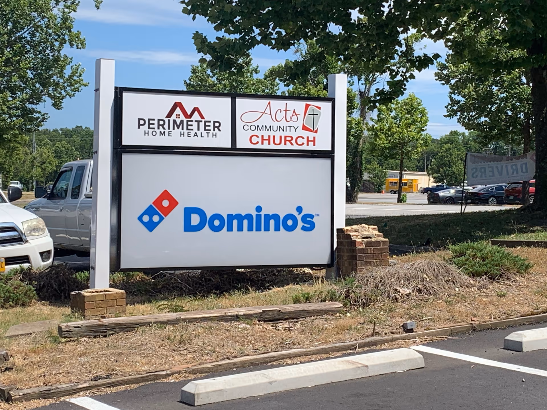 Outdoor sign displaying Perimeter Home Health and Domino's logos beside a parking lot