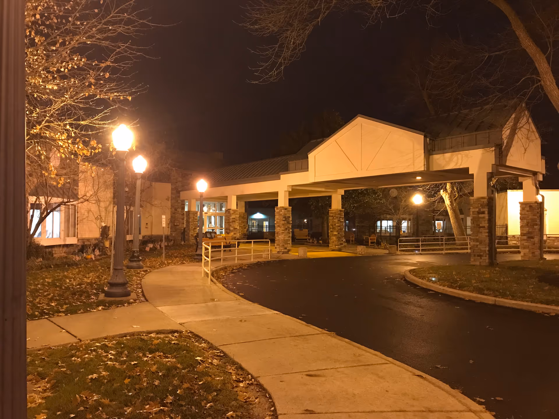 Nighttime exterior view of a veterans home entrance with illuminated walkway and covered drop-off.