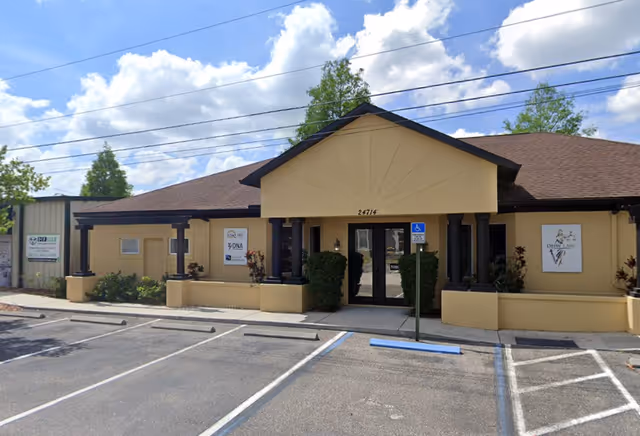 Front view of a single-story tan senior care building with a parking lot.
