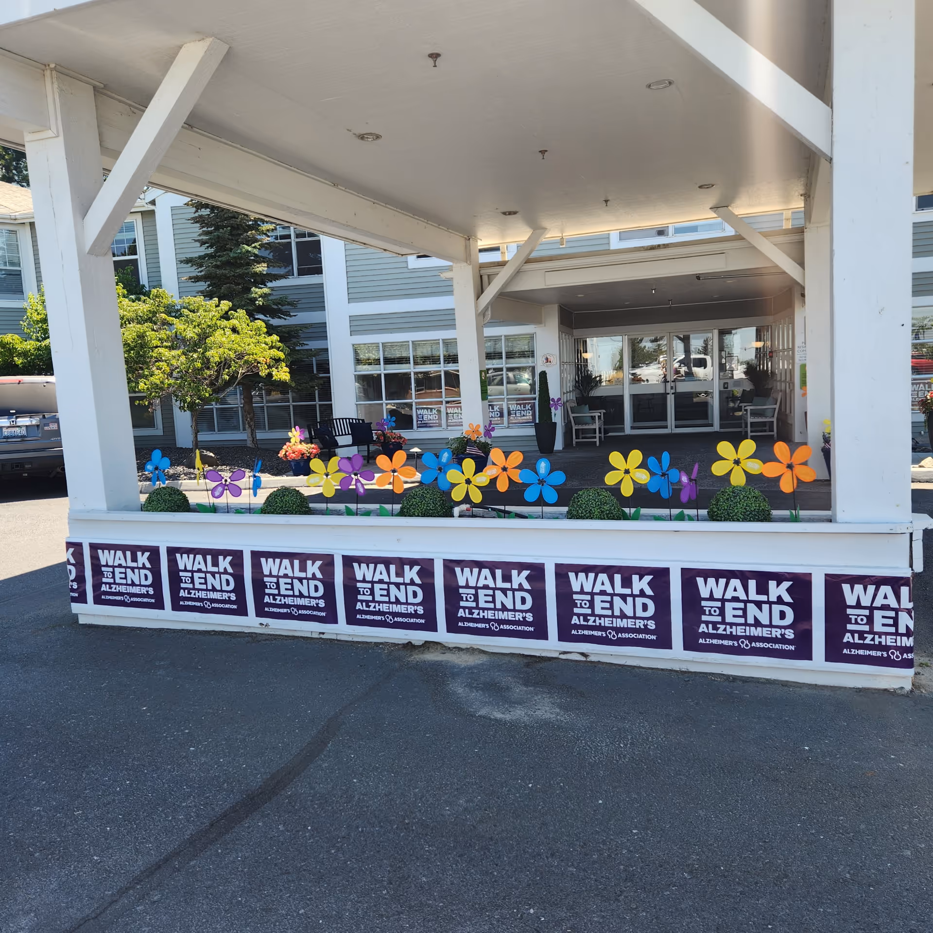 Front exterior of the facility with colorful pinwheels and Walk to End Alzheimer's banners.