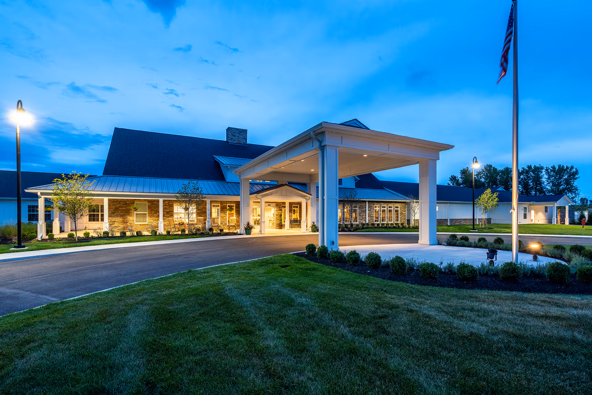 Walnut Crossing senior living facility at dusk with a covered entrance and manicured grounds.