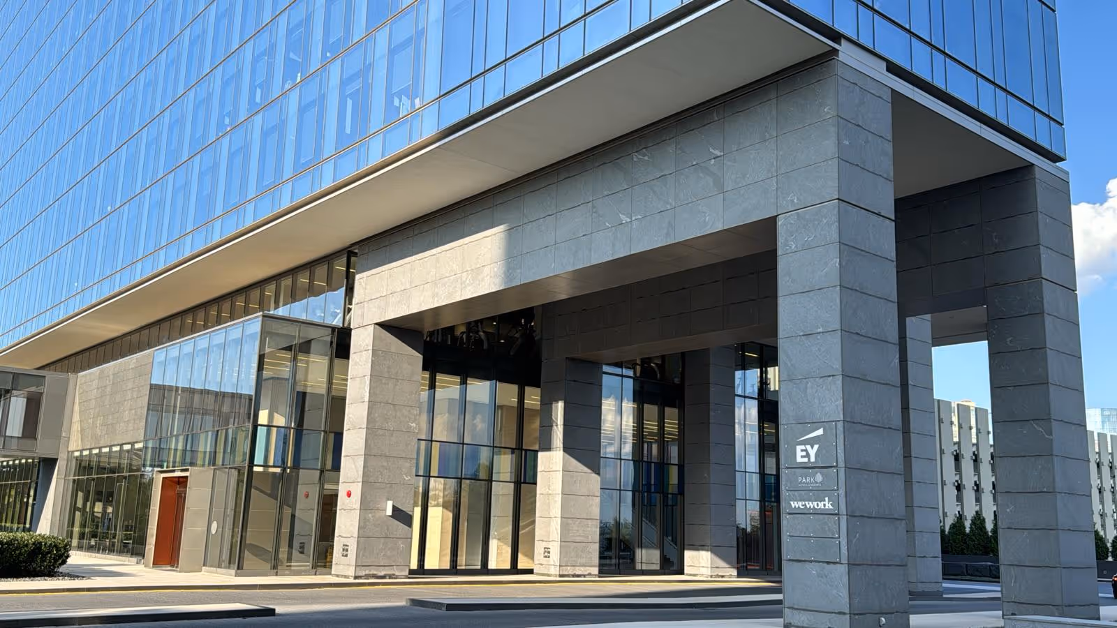 Modern glass and stone building entrance with large columns.