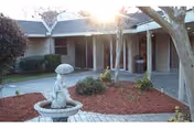 Exterior courtyard at a senior facility with a fountain, brick path, and trees.