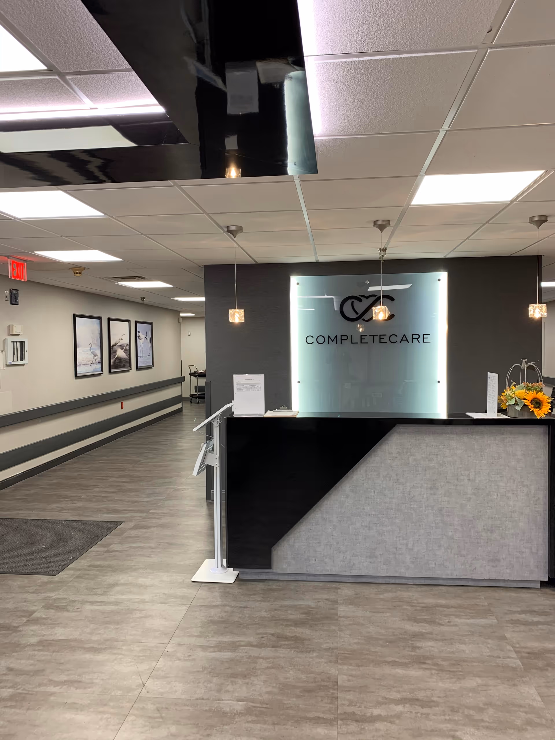 Reception desk with a frosted sign reading COMPLETECARE in a modern lobby.
