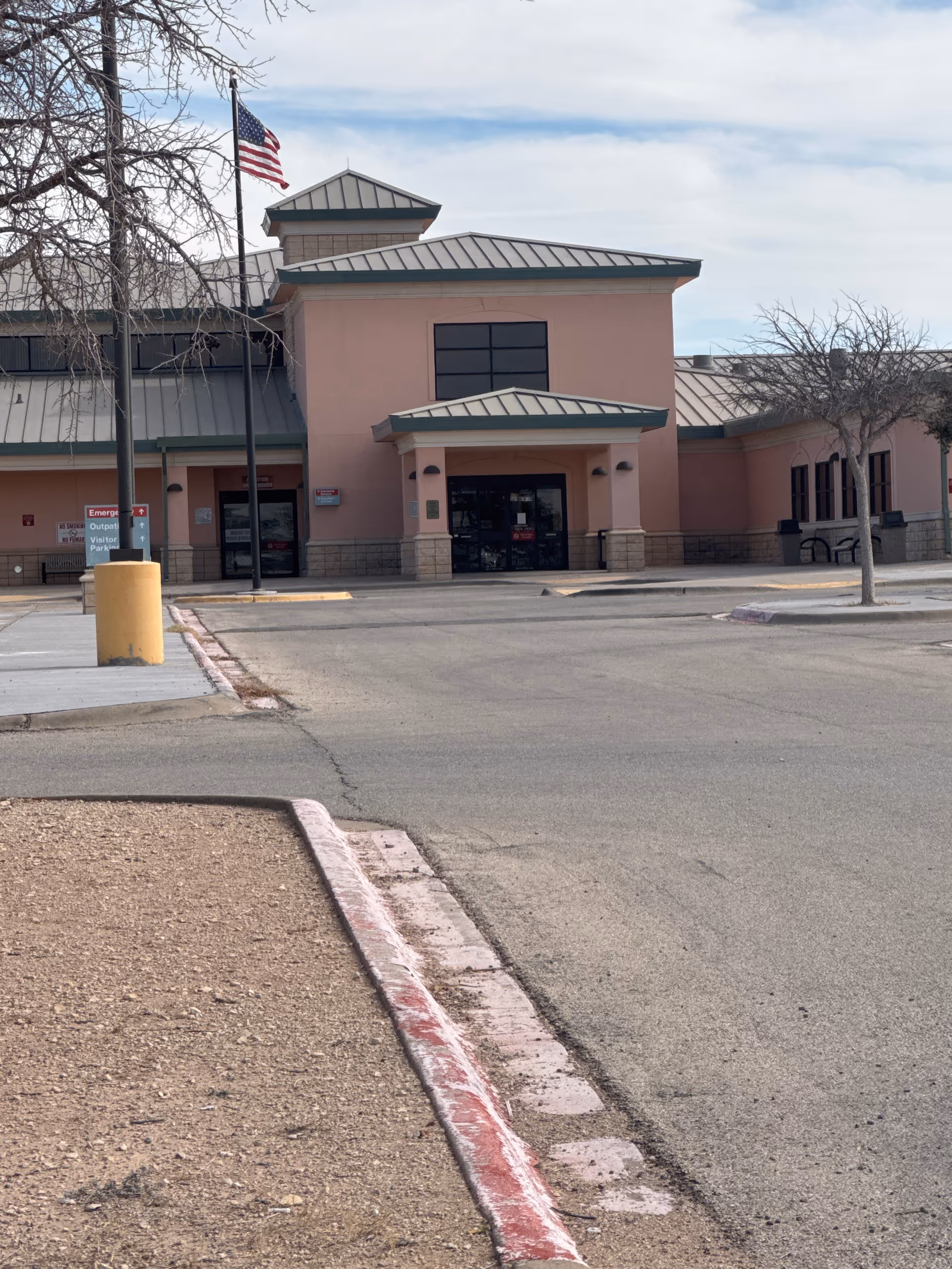 Pecos County Memorial Hospital exterior with pink walls, entrance canopy, and American flag.