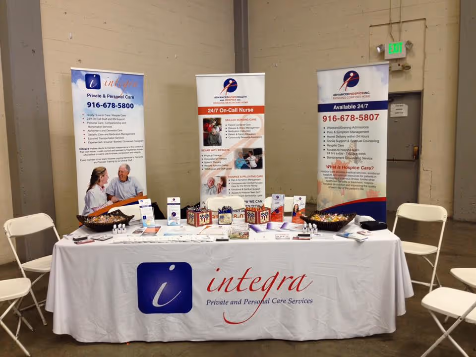 Promotional display table with banners and chairs inside a facility, Integra branding.