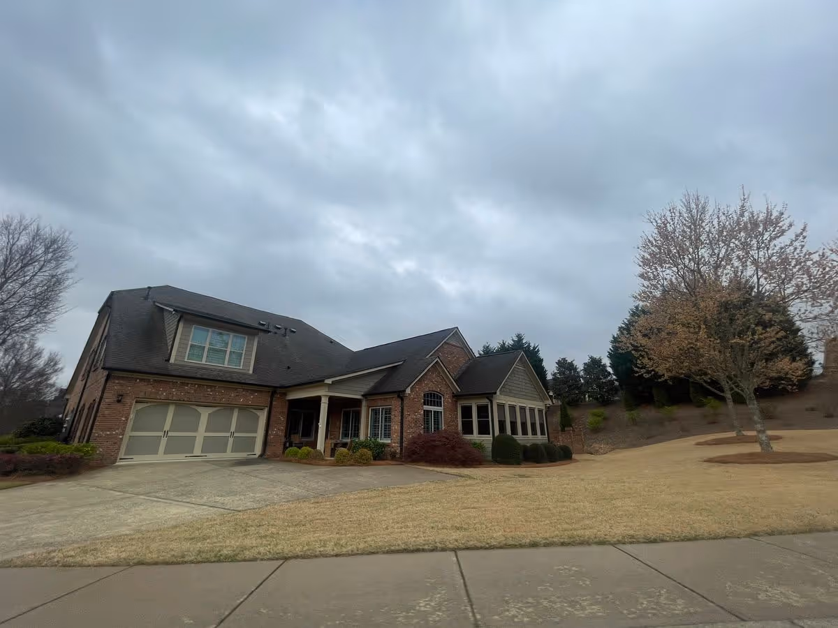 Brick senior living building with an attached two-car garage, driveway and lawn under a cloudy sky.