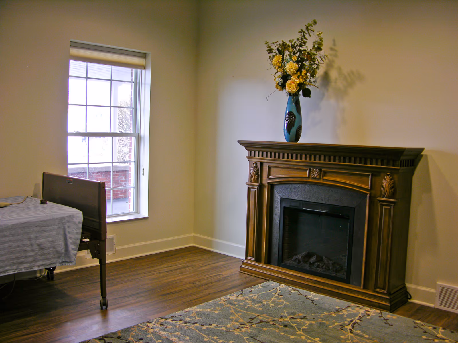 Cozy bedroom in a senior living facility with a decorative fireplace and bed.