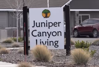 The Juniper Canyon Living sign stands in front of the building with desert landscaping.