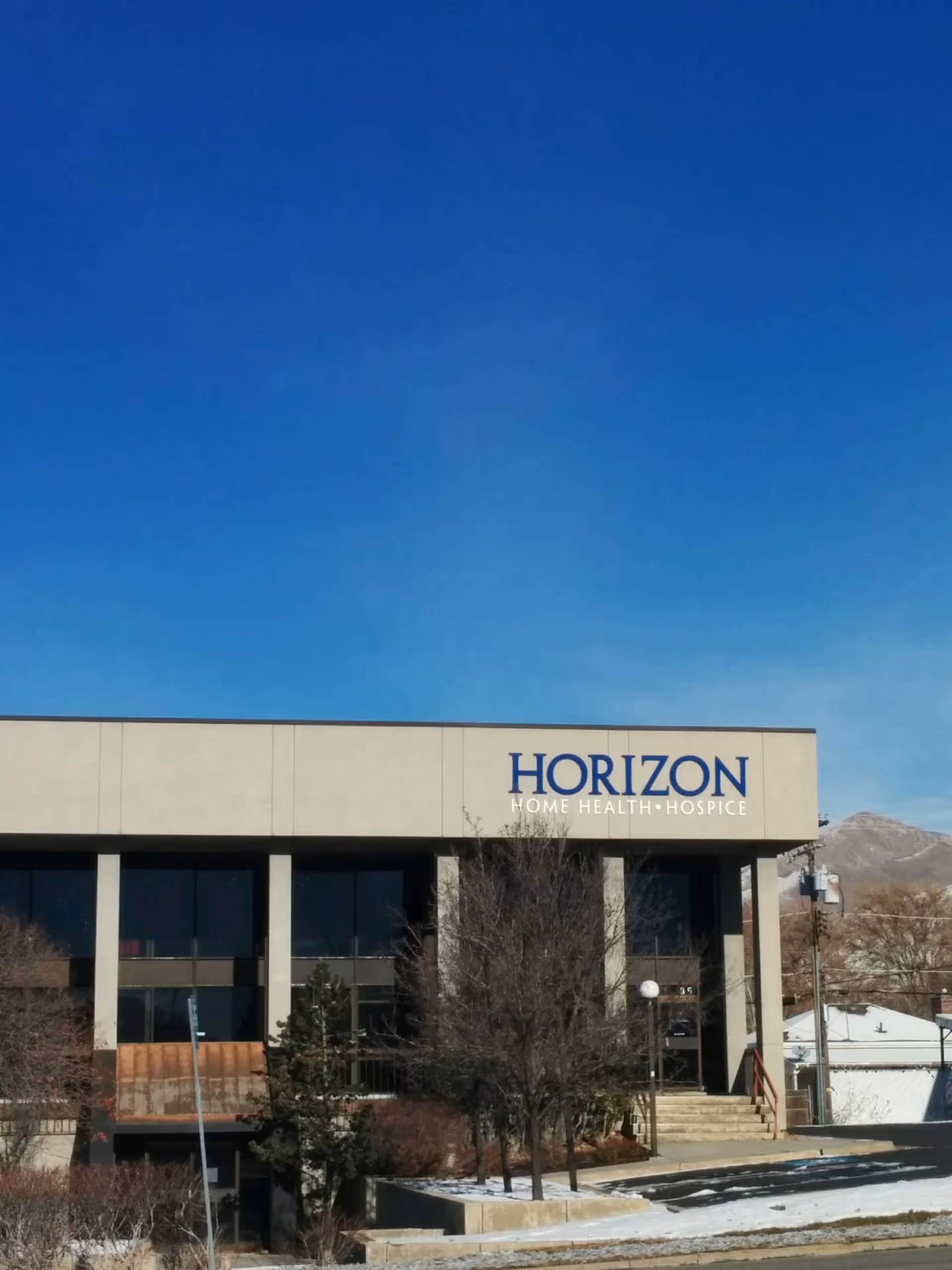 Sunlit exterior of Horizon Home Health Hospice building with a clear blue sky