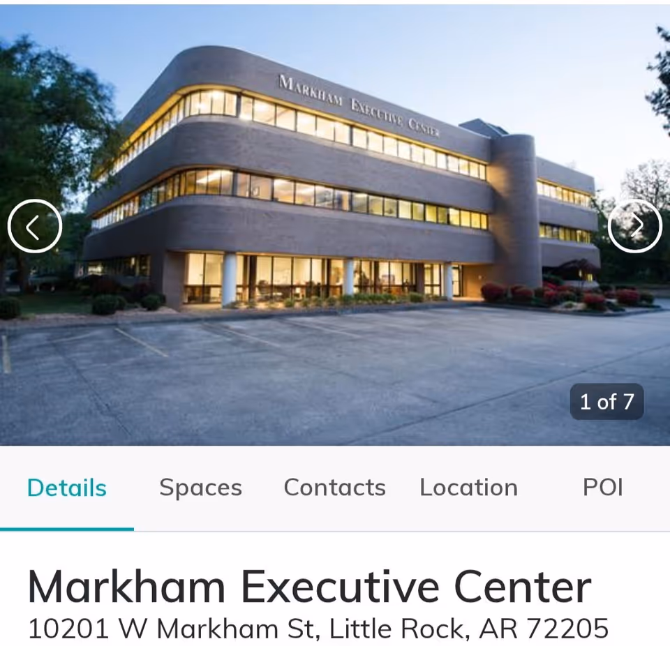 Contemporary three-story building with curved facade, large windows, and an expansive parking lot.