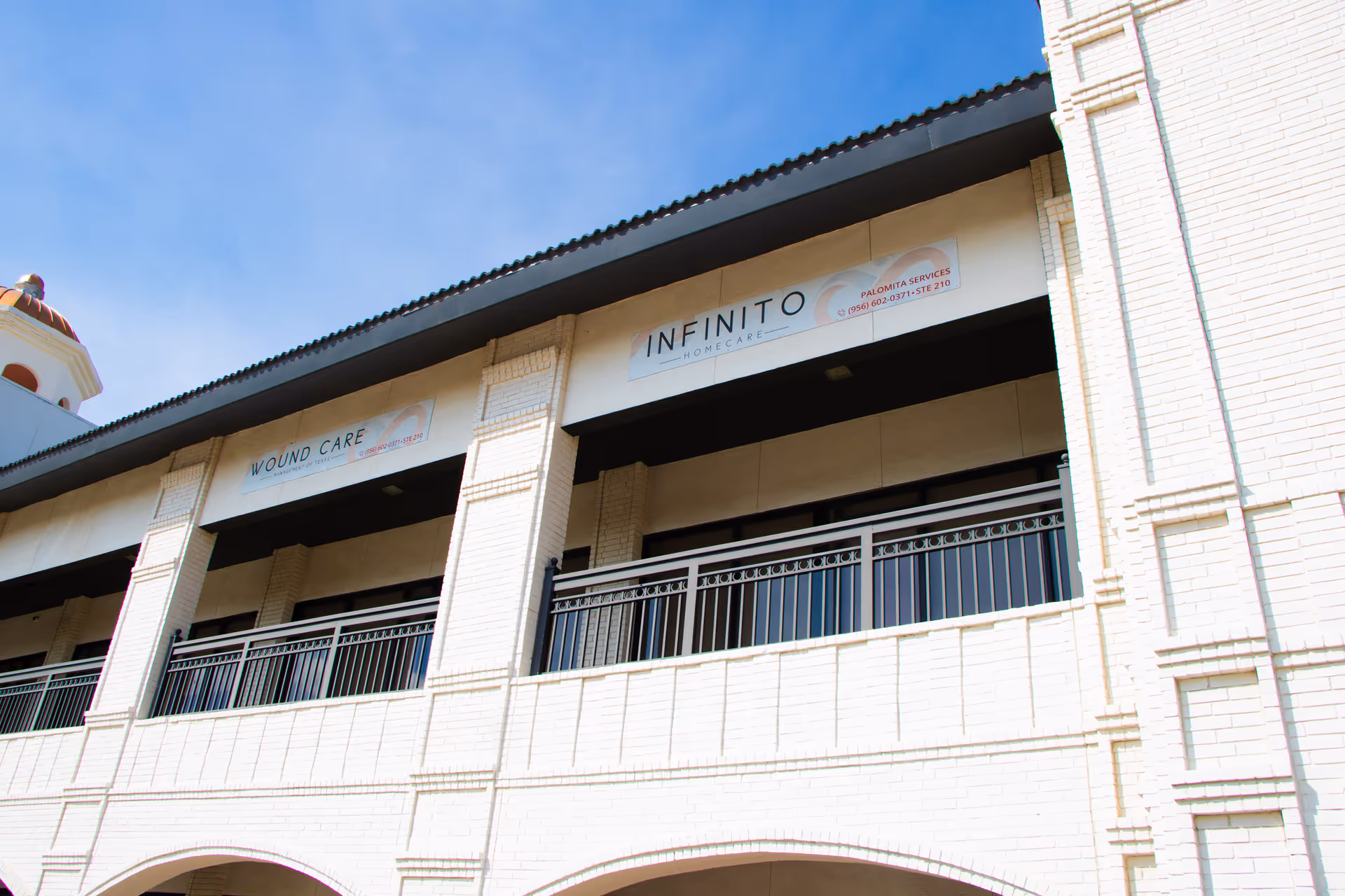 Exterior view of Infinito Homecare building with signs and balcony railing.
