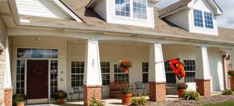 Front exterior of Brookdale Barberton with columns, porch seating, and potted plants.
