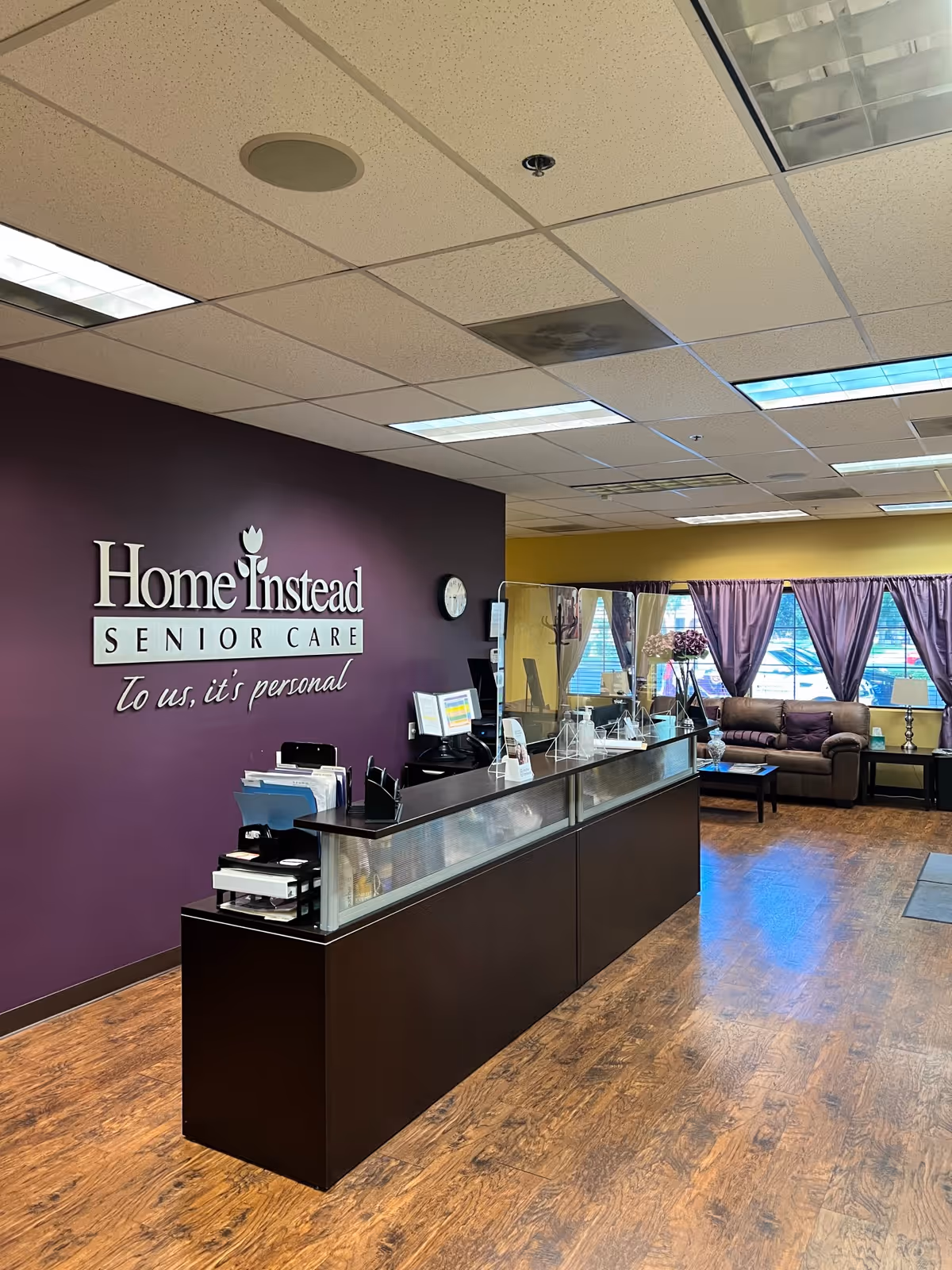 Reception area at Home Instead Senior Care with purple wall and seating.