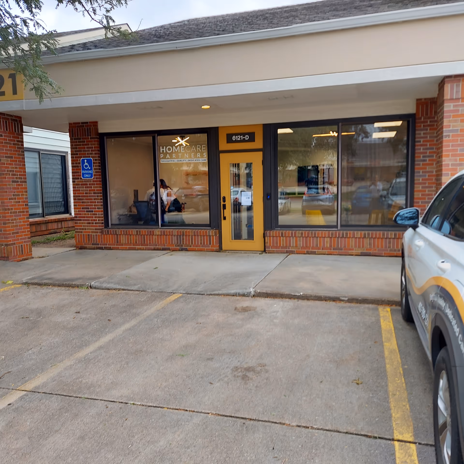 Front exterior of HomeCare Partners building with brick facade, large windows, and a yellow door.