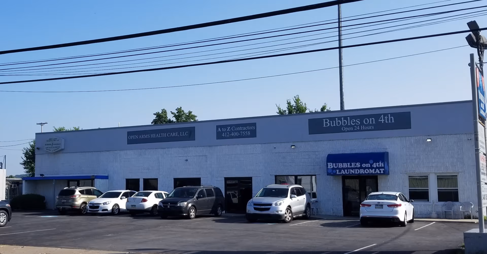 Exterior view of a single-story building with Open Arms Health Care, LLC signage and parked cars.