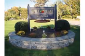 Outdoor sign for Apple Rehab Saybrook in a circular stone planter with shrubs.