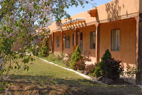 Exterior view of tan retirement village buildings with a landscaped walkway and shrubs.