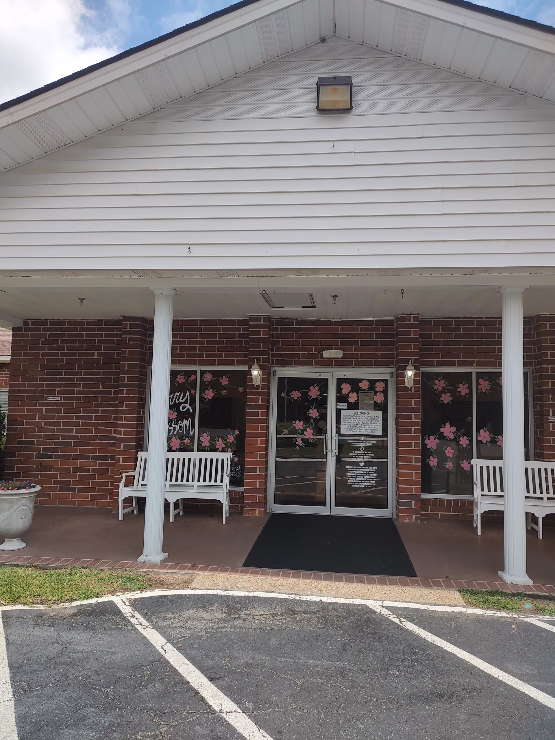 Front entrance of Cherry Blossom Health and Rehabilitation with brick facade, glass doors, and flower decorations.