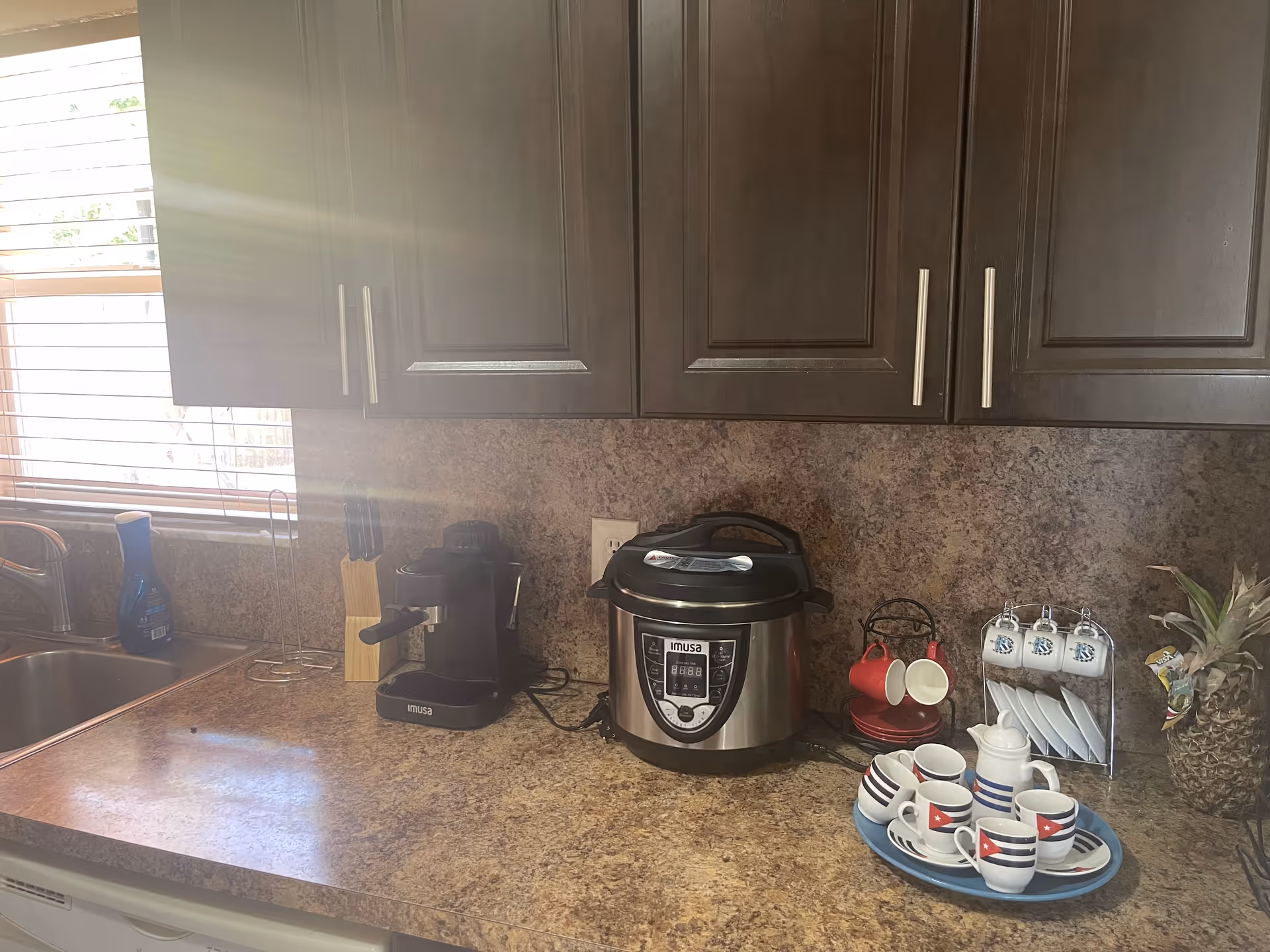Dark cabinets above a counter with a coffee maker, Instant Pot, and mugs.