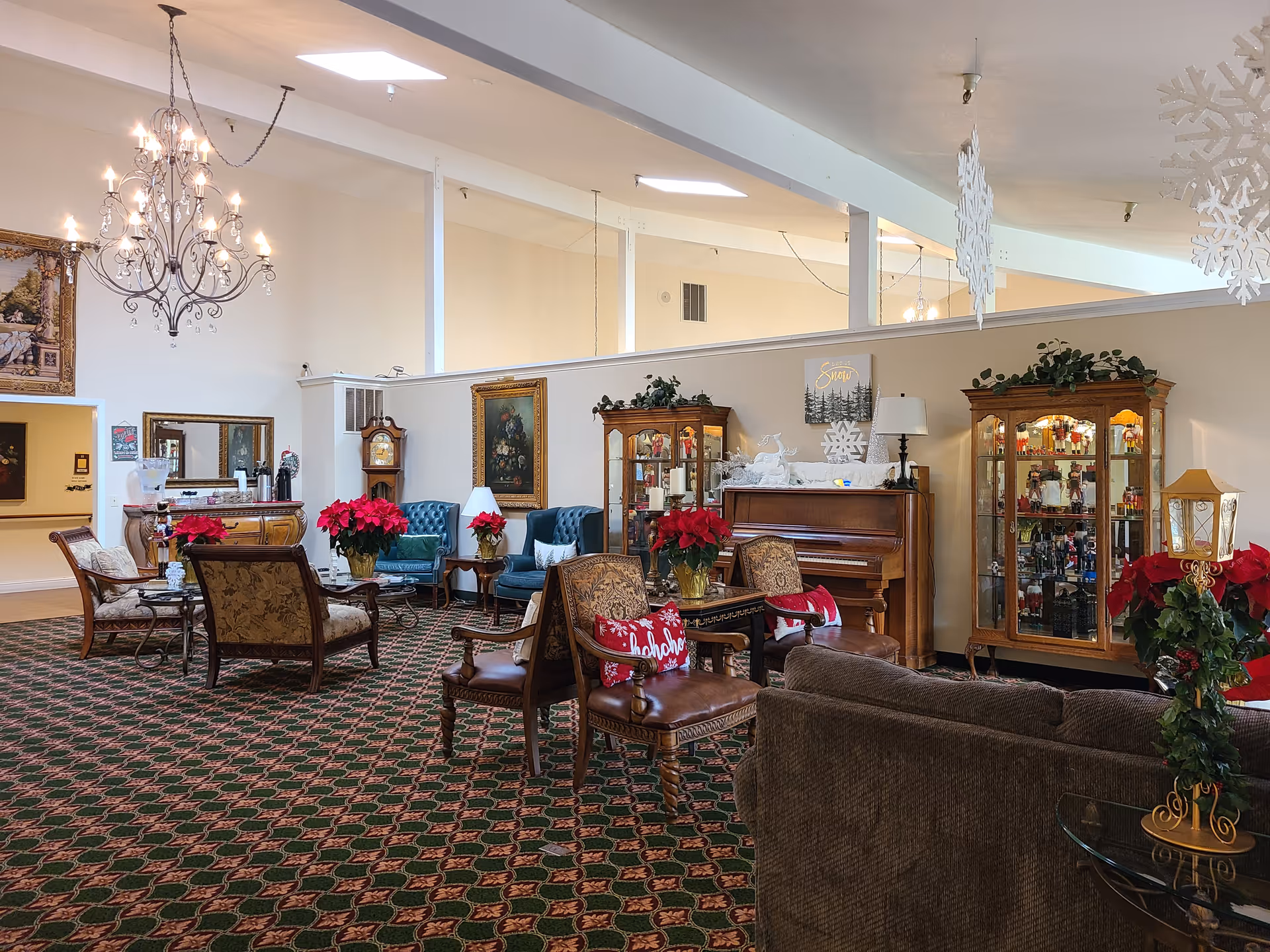 Elegant senior living lobby with sofas, chairs, crystal chandelier, and holiday decorations.