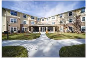 Exterior view of a multi-story senior living building with a central covered entrance.