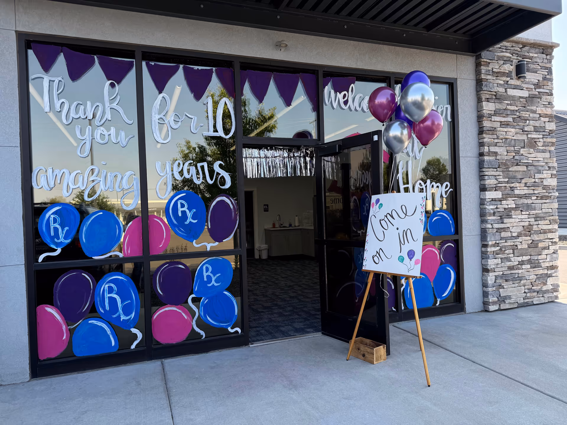Storefront entrance decorated with balloons and signage for a 10-year celebration at Happier At Home.