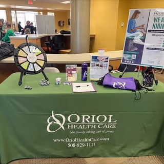 Lobby reception area with an Oriol Health Care table, wheel, brochures, and posters.