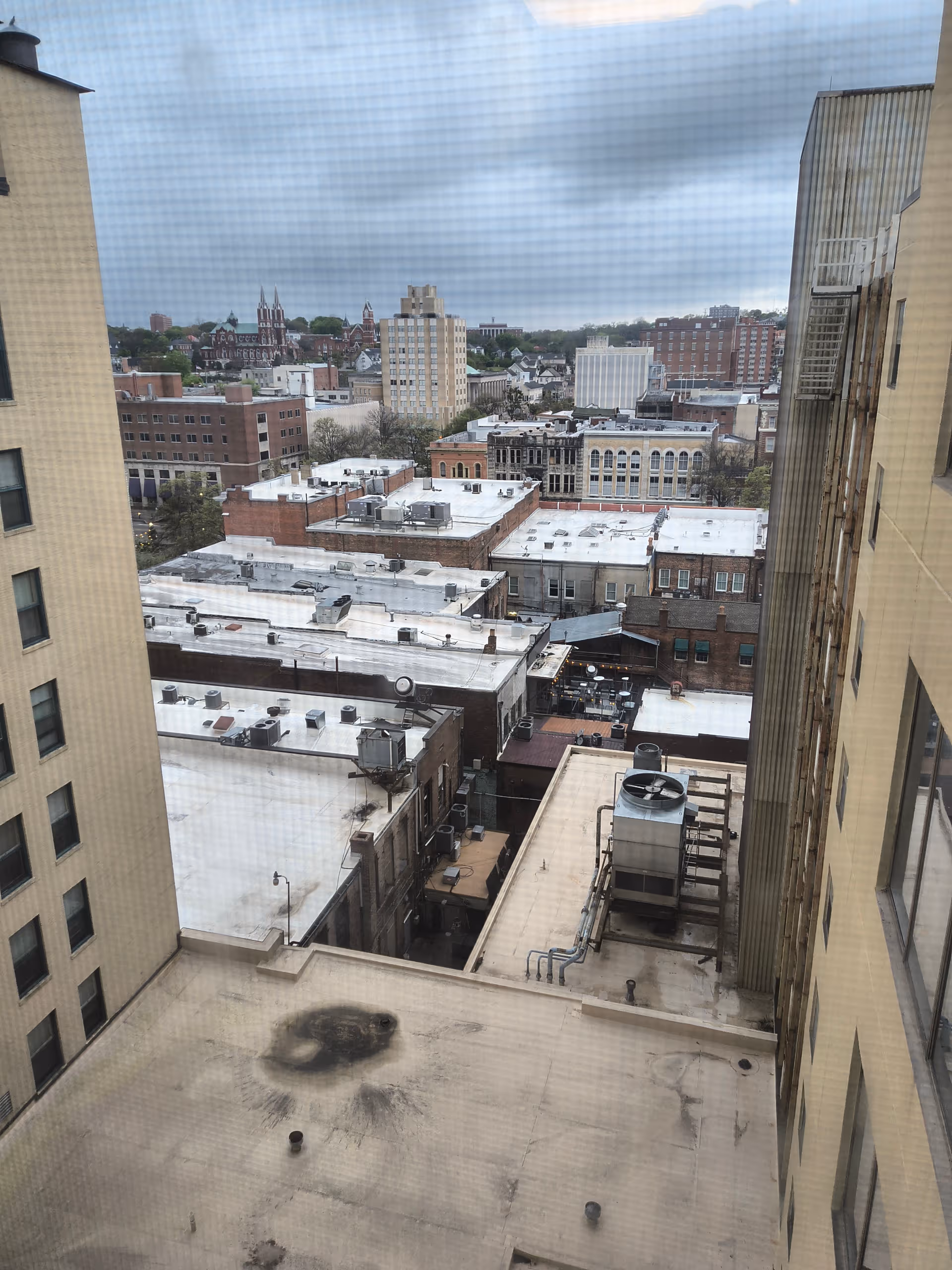 View from a high-rise window overlooking city rooftops and distant skyline.