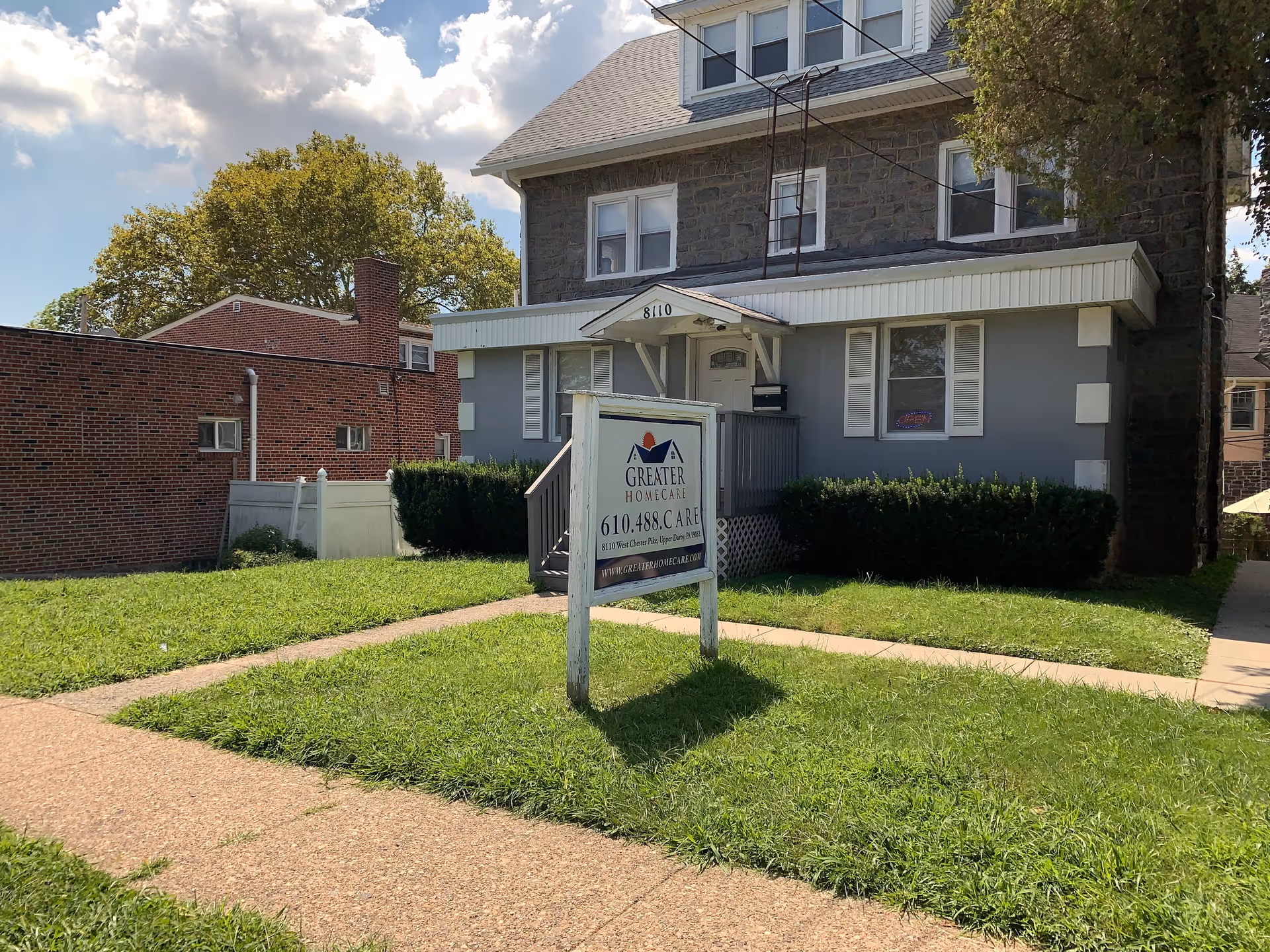 Front view of a two-story building with a sign in the grassy front yard.