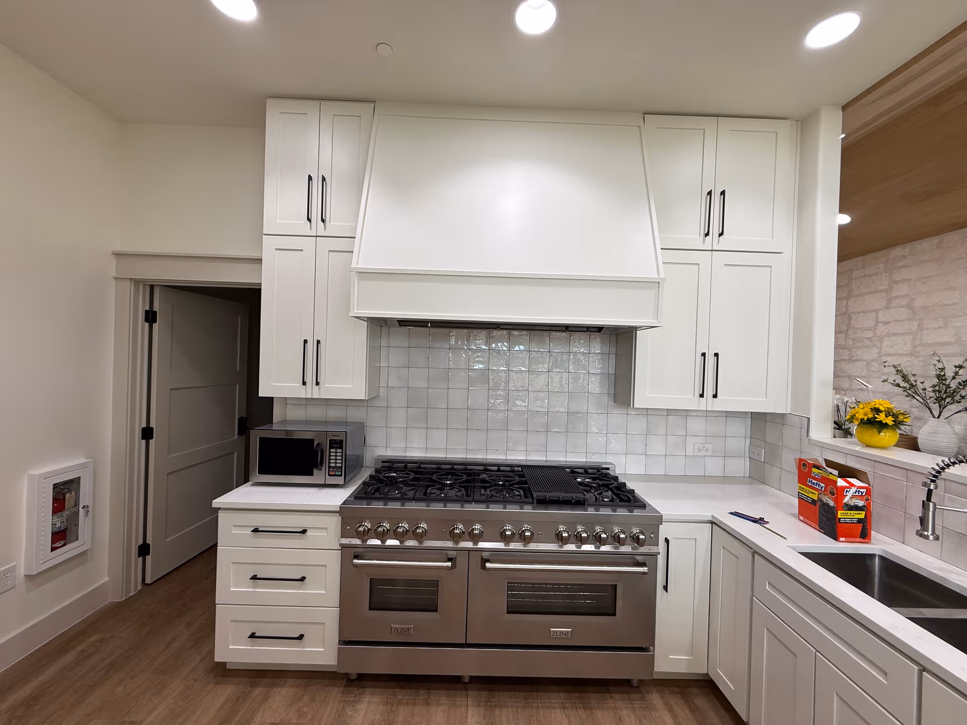 White modern kitchen at The Ponderosa Estate with stainless stove, hood, cabinets, and sink.