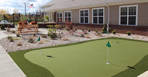 Outdoor view of a building with a putting green and landscaped garden beds.