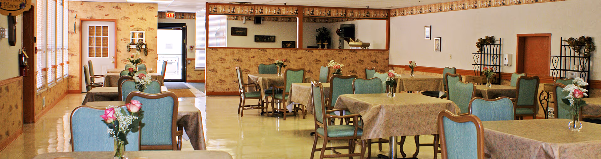 Dining room at Wyant Woods Care Center with tables, chairs, and floral centerpieces.