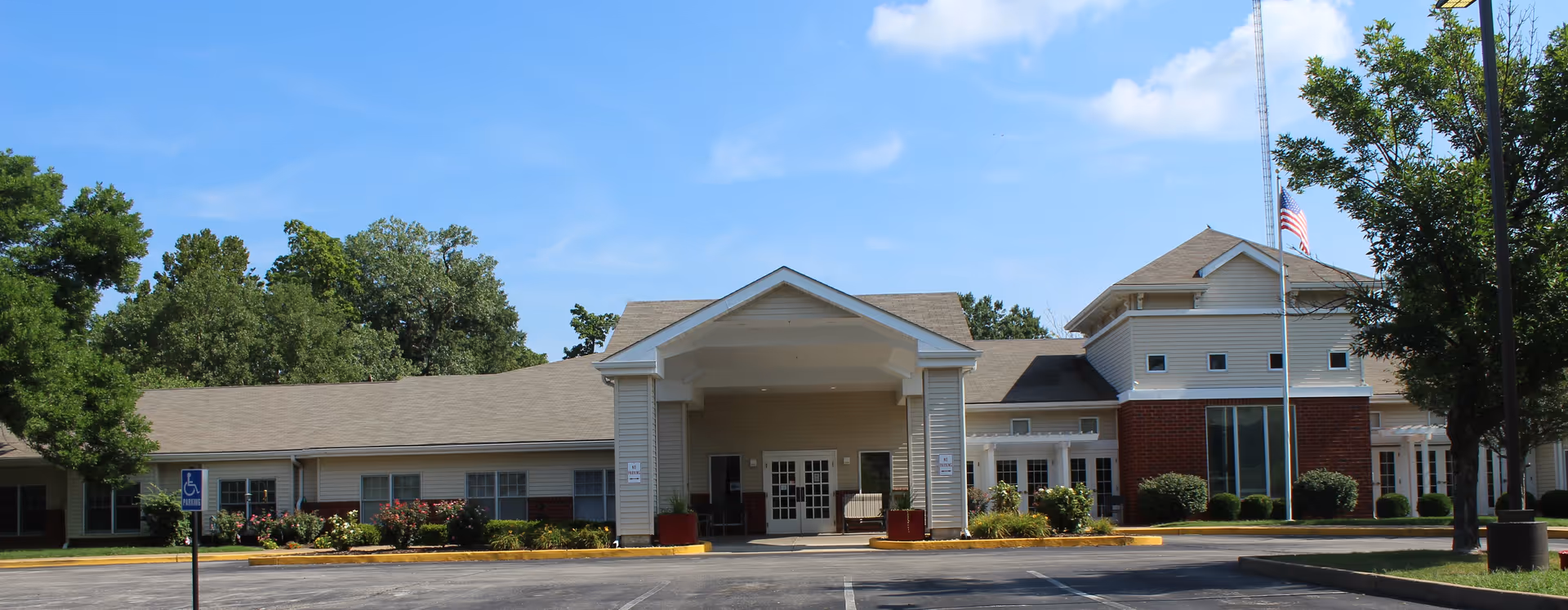 Front view of a senior living residence with a porte-cochere entrance and manicured landscaping.