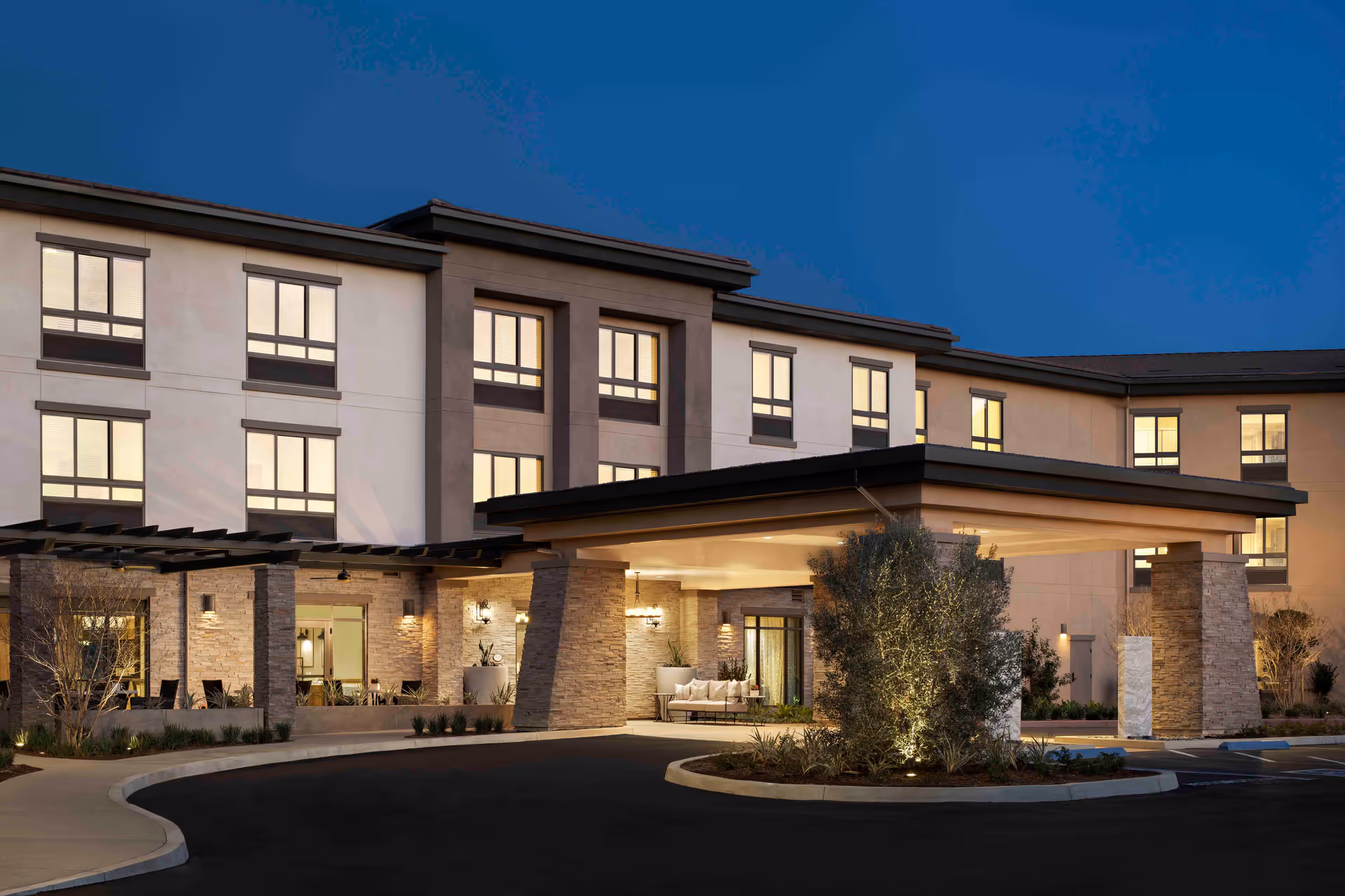 Exterior view of Belmont Village Senior Living Aliso Viejo at dusk with illuminated entrance.